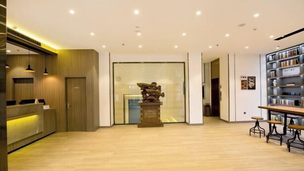 Een modern interieur met een receptiebalie, een standbeeld en een boekenplank.