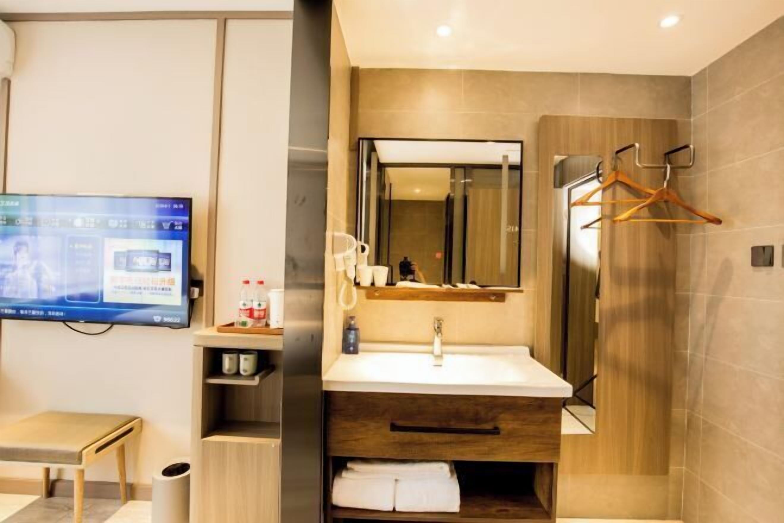 A modern bathroom with a large mirror, a sink, and a towel rack.
