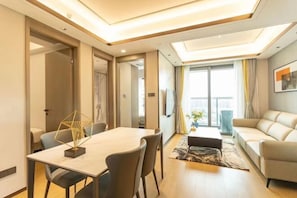 A modern living room with a dining area, a sofa, and a large window with curtains. - Senmei International Apartment (Shenzhen Window of the World) (Shenzhen)