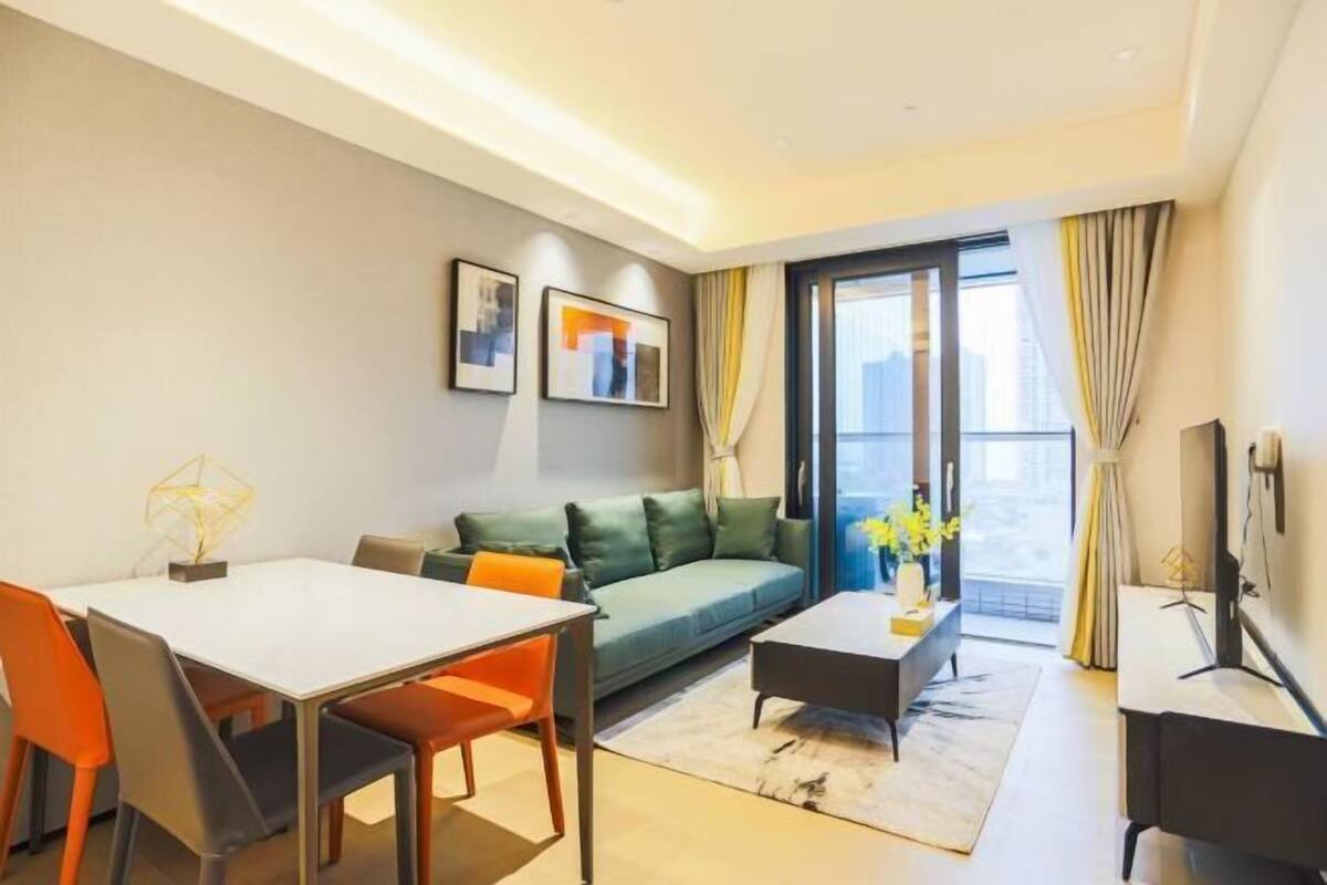 Ein modernes Wohnzimmer mit einer Couch, einem Esstisch, Stühlen, einem Couchtisch und einem Fernseher.
