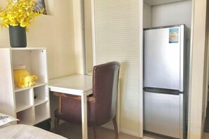 A room with a bed, a desk, a chair, a refrigerator, and a shelf with a teddy bear. - Weimena International Homestay (Shenzhen Window of the World) (Shenzhen)