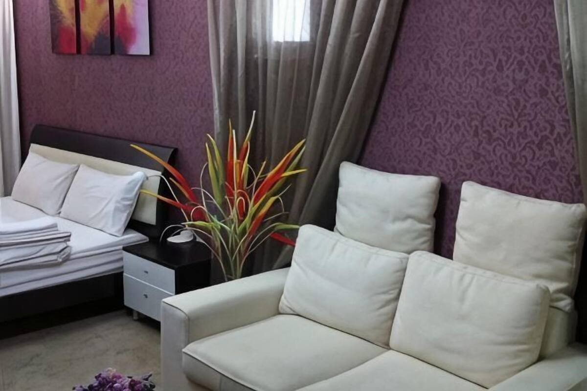 Ein Hotelzimmer mit Bett, Sofa, Nachttisch und einer Zimmerpflanze.