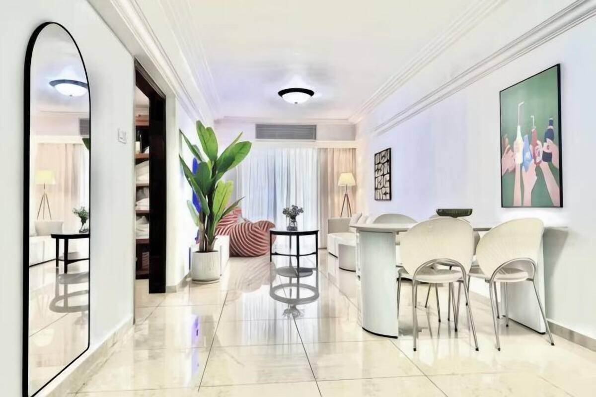 Eine moderne Hotelhalle mit großem Spiegel, einer Rezeption, einer Sitzecke und einer großen Pflanze.