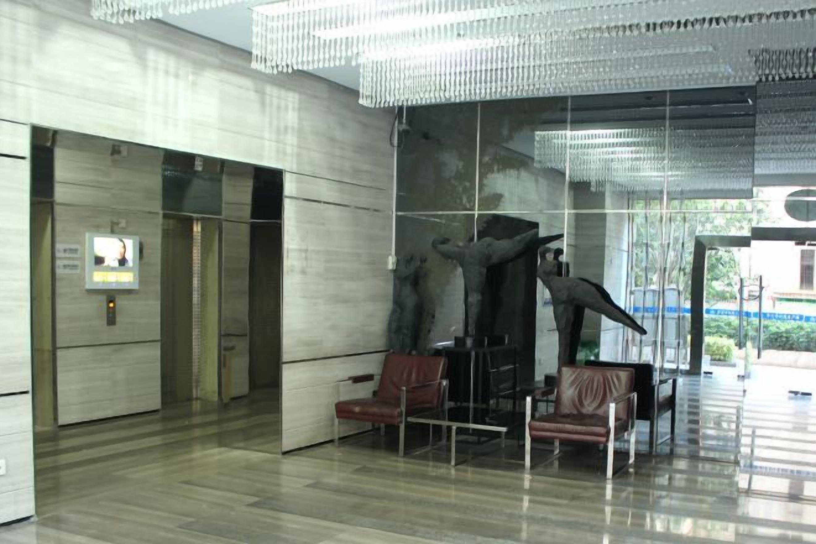 A lobby with a modern design, featuring a large sculpture, seating area, and a glass wall.