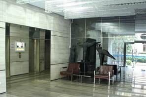 Un vestíbulo con diseño moderno, que presenta una gran escultura, zona de estar y un muro de cristal.
