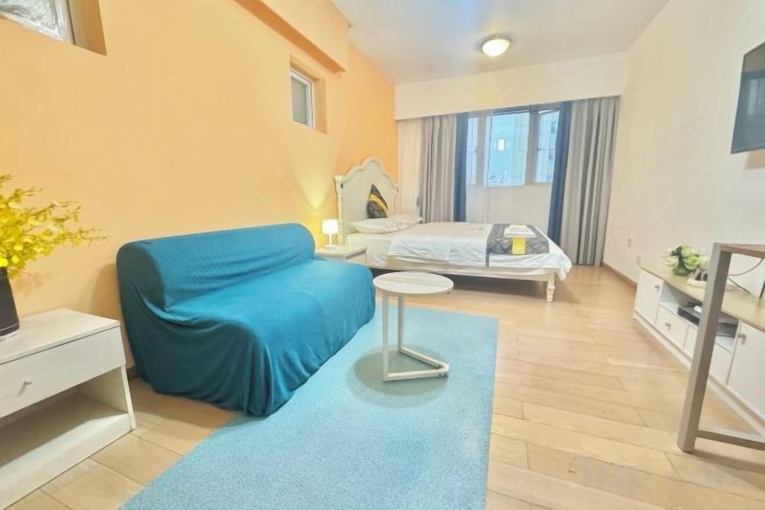 A bedroom with a bed, a blue sofa, a bedside table, and a small round table.