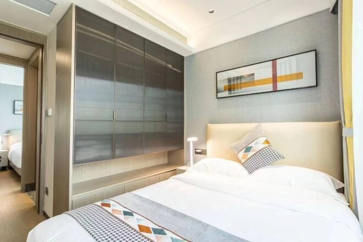 Ein Hotelzimmer mit großem Kleiderschrank, einem Bett mit gemusterten Bettwaren und einem modernen abstrakten Gemälde an der Wand.