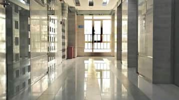 A corridor with reflective floors and glass doors leading to a bright interior space.