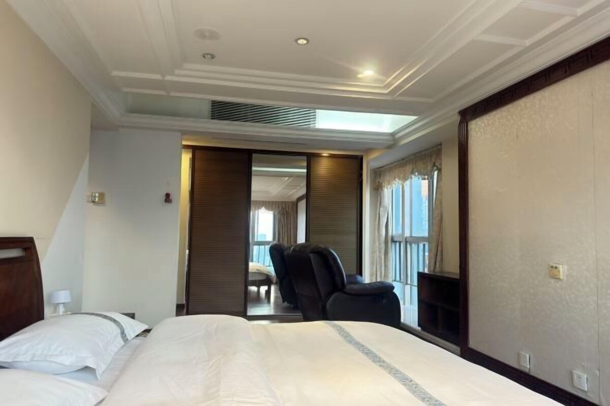 Habitación de hotel con una cama grande, una silla, un escritorio y vistas al exterior.