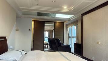 Habitación de hotel con una cama grande, una silla, un escritorio y vistas al exterior.