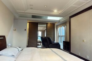 Habitación de hotel con una cama grande, una silla, un escritorio y vistas al exterior.