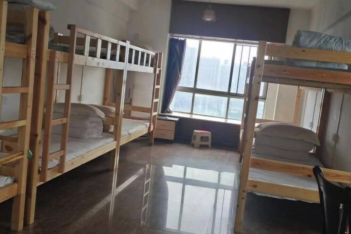 Una habitación con literas, un escritorio pequeño y una ventana con vistas a edificios.