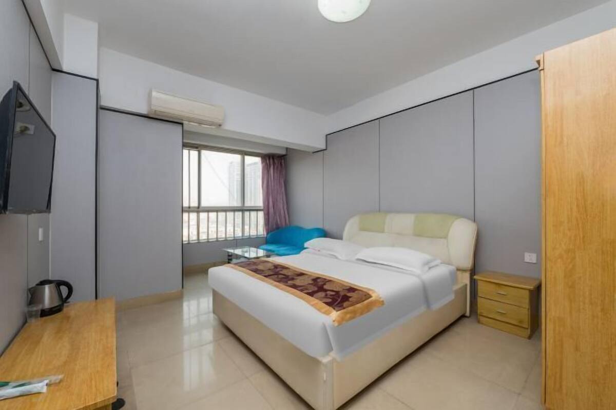 Un dormitorio moderno con cama, mesita de noche y televisor montado en la pared.