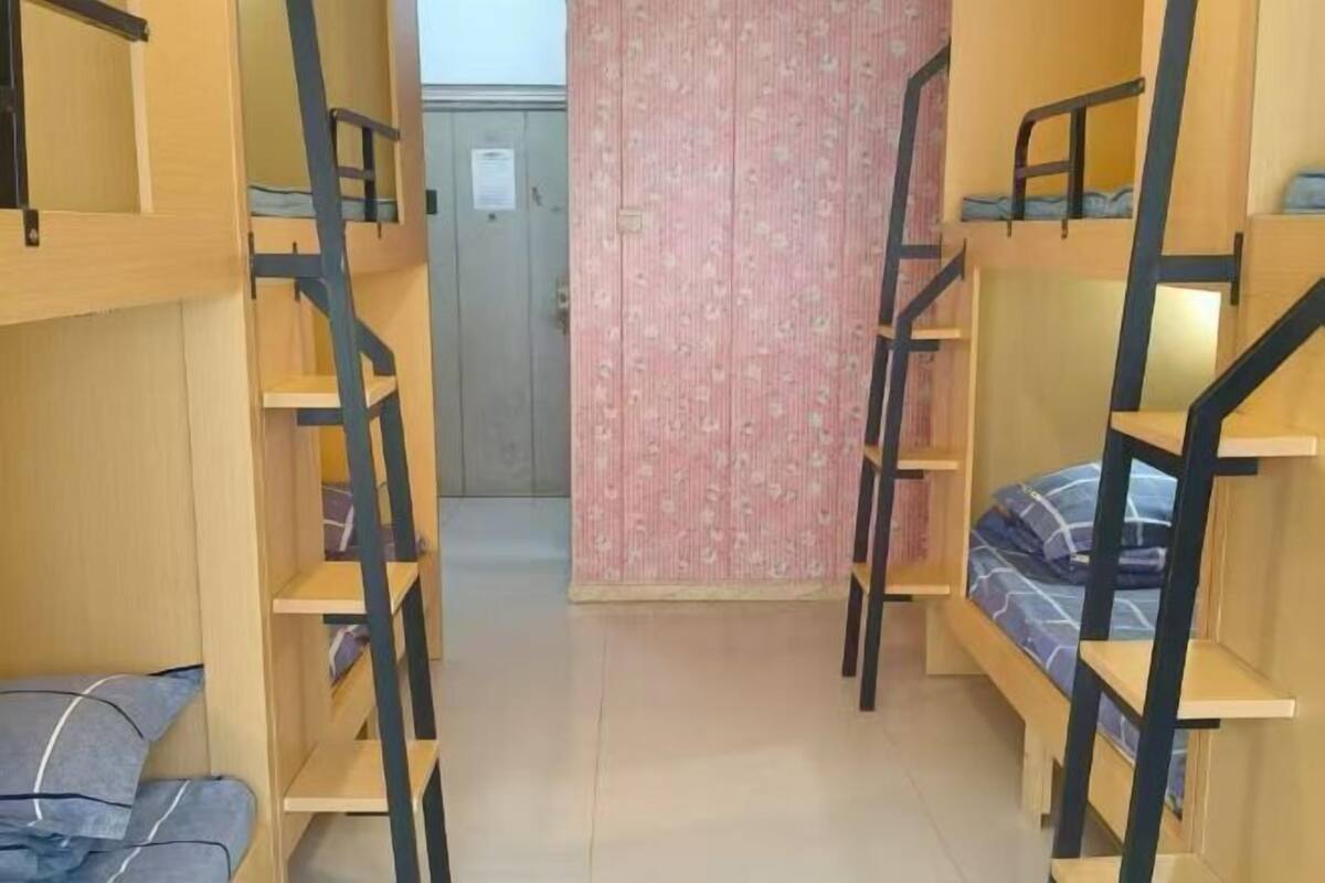 Un dormitorio con literas, pared con estampado rosa y una puerta al fondo.