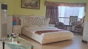 Un dormitorio con una cama, una mesita de vidrio, una silla, un escritorio y una ventana con cortinas.