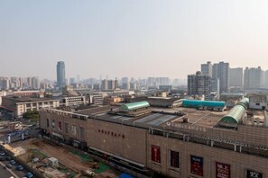 Un grand bâtiment industriel à plusieurs étages, doté d’un toit plat, entouré d’un paysage urbain composé d’immeubles de grande hauteur.
