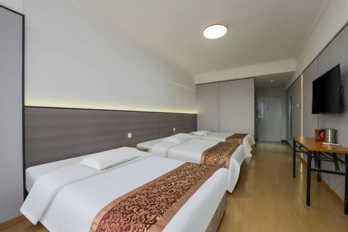 Habitación de hotel con dos camas, televisión y escritorio.