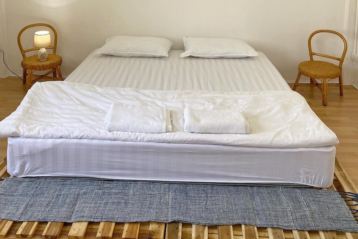 Une chambre à coucher avec un grand lit, deux tables de chevet et un tableau encadré au mur.