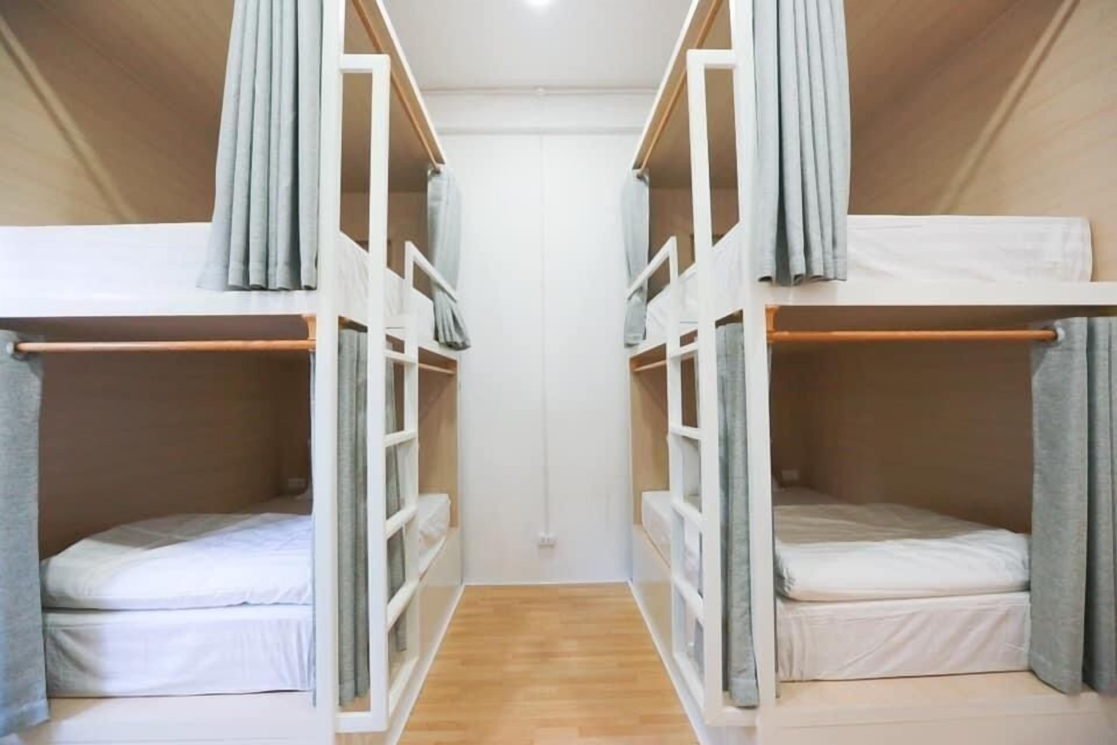 A room with two bunk beds, wooden flooring, and a white door.