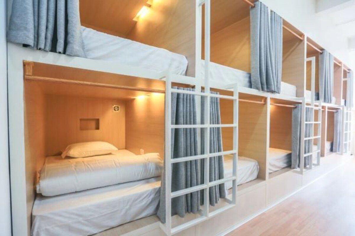 A bunk bed room with white bedding and grey curtains.