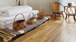 Un dormitorio con cama, una silla, una mesa y una lámpara de pared.