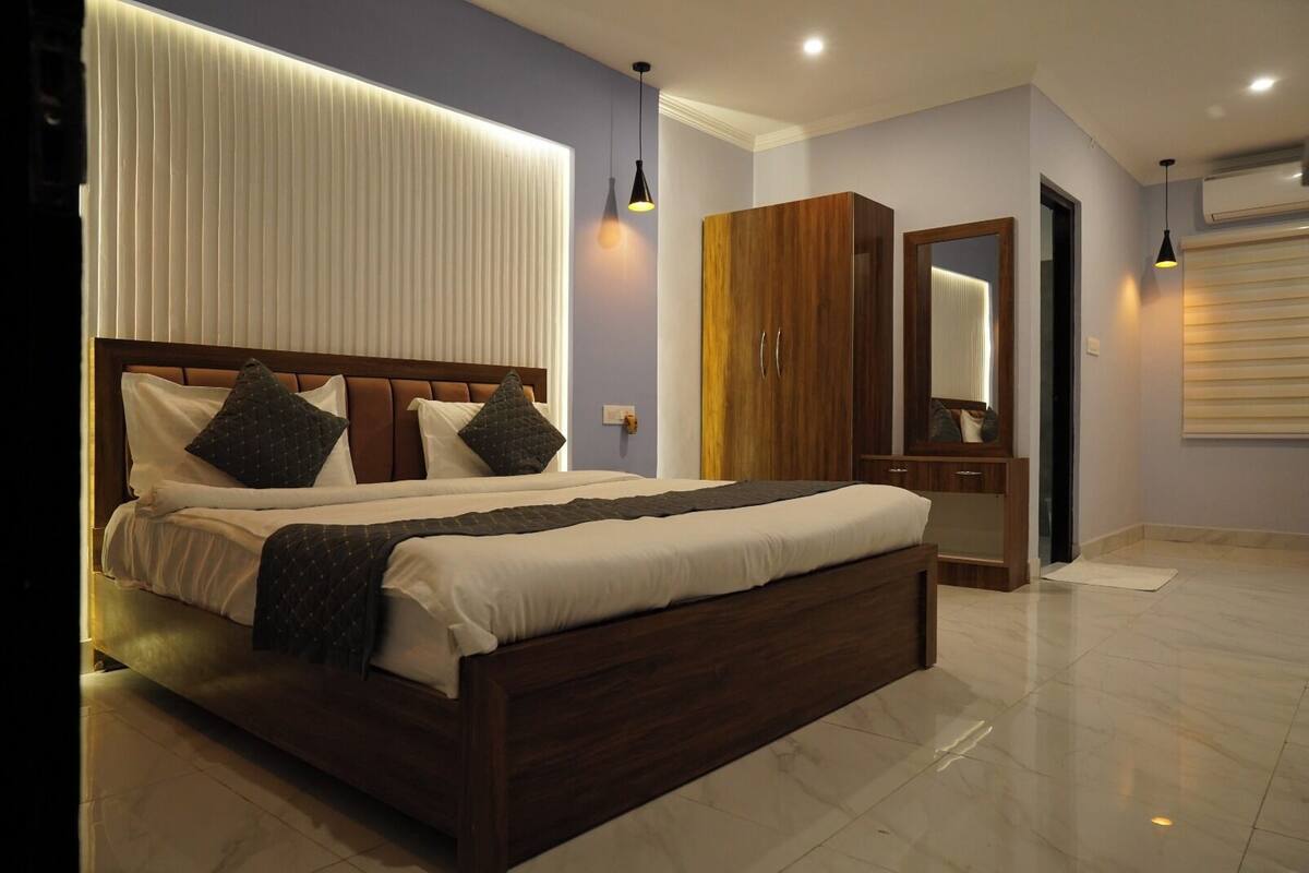 Une chambre moderne avec un grand lit, une tête de lit en bois et une armoire.