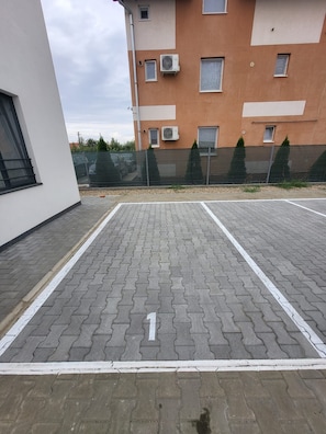 Un espace de stationnement sur le toit, avec des dalles grises emboîtées et des lignes blanches délimitant les places de stationnement.
