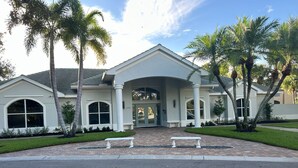 A two-story building with a symmetrical facade, large windows, and a central entrance with a covered walkway. - The Villa at Marsh Landing!  3Bed/2 bath townhome in the heart of Estero! (Estero)