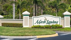 A sign for 'Marsh Landing' with a landscaped area and palm trees in the background. - The Villa at Marsh Landing!  3Bed/2 bath townhome in the heart of Estero! (Estero)