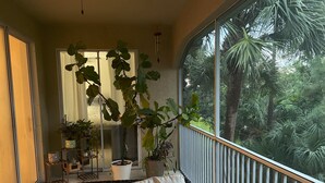 A balcony with a sofa, potted plants, and a view of a lush garden. - The Villa at Marsh Landing!  3Bed/2 bath townhome in the heart of Estero! (Estero)