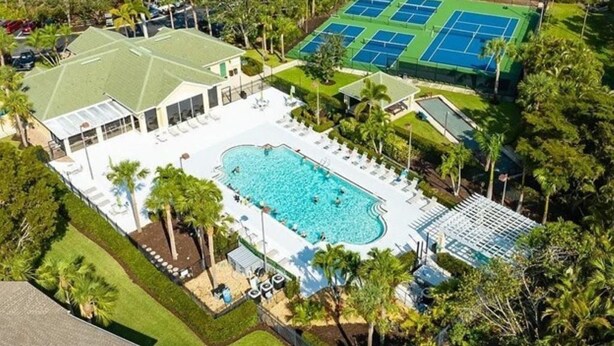 An aerial view of a resort with a large swimming pool, tennis courts, and a covered area with lounge chairs. - The Villa at Marsh Landing!  3Bed/2 bath townhome in the heart of Estero! (Estero)