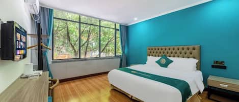 Une chambre d’hôtel avec un lit, un bureau et une fenêtre donnant sur des arbres.