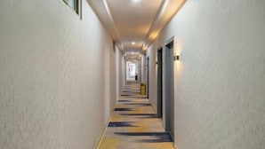 A long, narrow hotel hallway with a patterned carpet, recessed lighting, and doors on both sides. - Yumei Yipin Hotel (Guangzhou Panyu Shiqiao Branch) (Guangzhou)