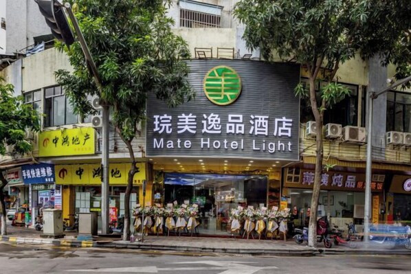 A hotel with a prominent sign, outdoor seating, and a street view.