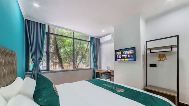 A hotel room with a large bed, a TV on the wall, and a window with curtains. - Yumei Yipin Hotel (Guangzhou Panyu Shiqiao Branch) (Guangzhou)