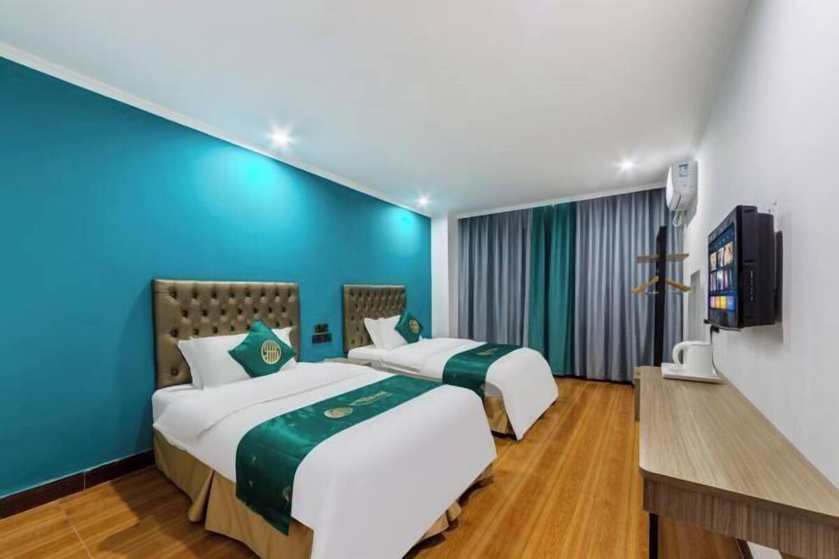 Une chambre d’hôtel avec deux lits, un bureau, une télévision et une fenêtre avec des rideaux.