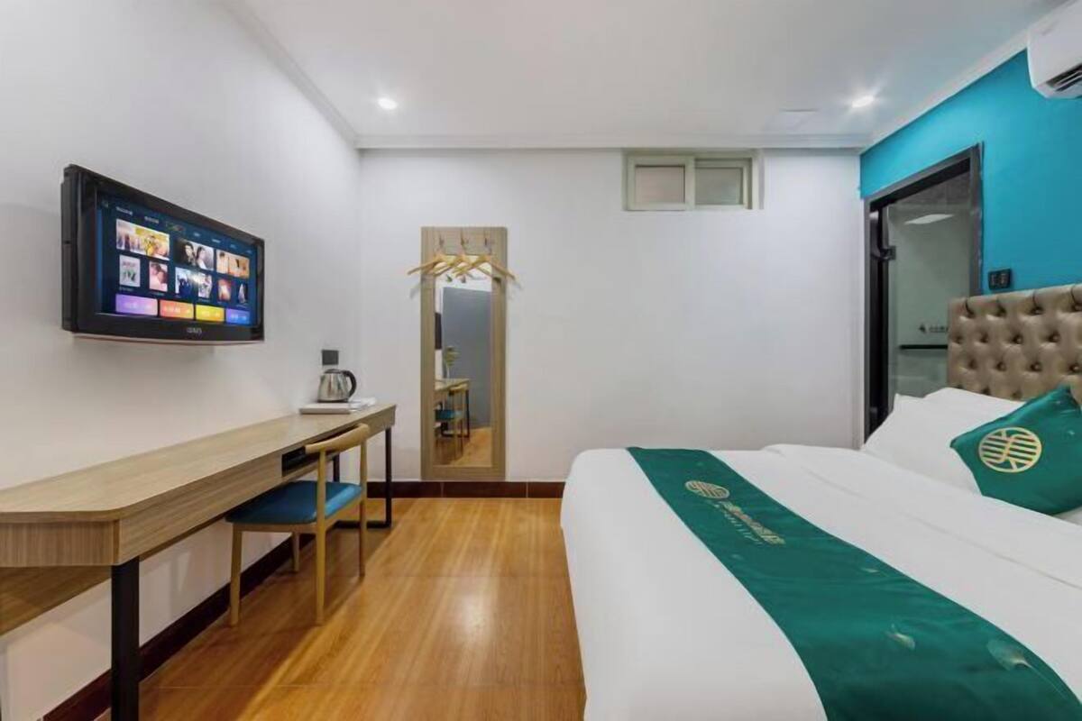 Une chambre d’hôtel avec un lit, un bureau, une télévision et un miroir.