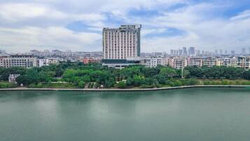 A high-rise building with a modern design, surrounded by a body of water and greenery.