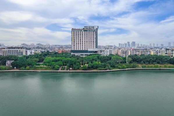 A high-rise building with a modern design, surrounded by a body of water and greenery.