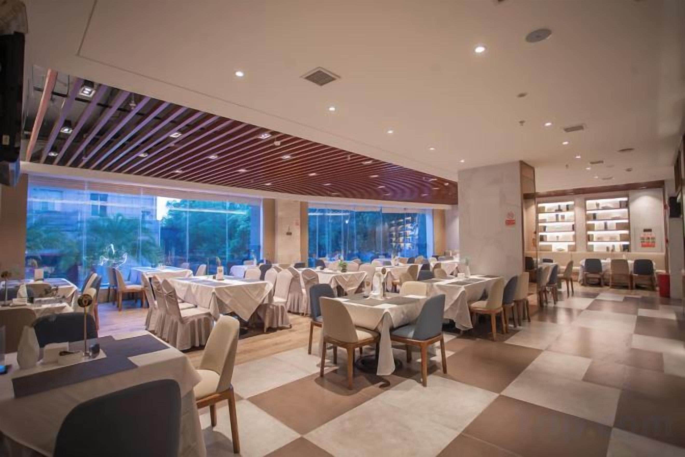 A restaurant with multiple tables and chairs, large windows, and a checkered floor.