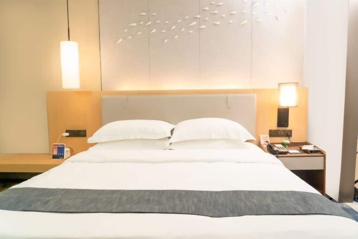 Een hotelkamer met een bed, nachtkastjes, een lamp en een wandlamp.