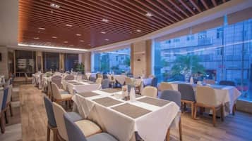 Un restaurante con mesas dispuestas para comer, ventanas amplias y un diseño de techo moderno.