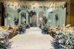 Un salón de banquetes con una larga mesa, decoración floral y un escenario con arcos.