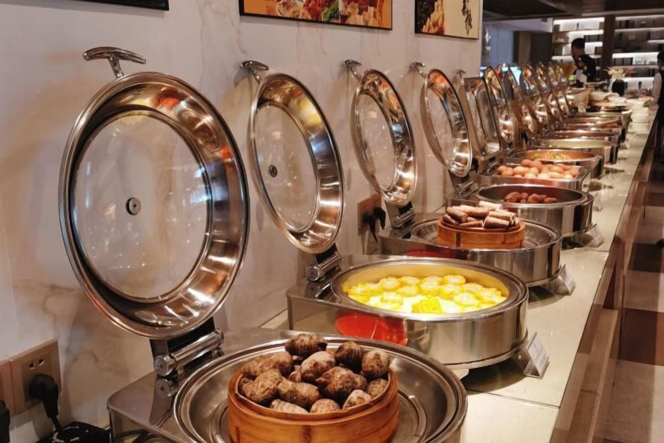 A buffet line with various food items, including a bowl of dumplings and a tray of scrambled eggs.