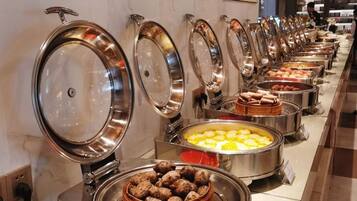 A buffet line with various food items, including a bowl of dumplings and a tray of scrambled eggs.