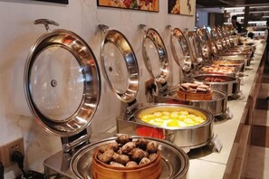 A buffet line with various food items, including a bowl of dumplings and a tray of scrambled eggs.