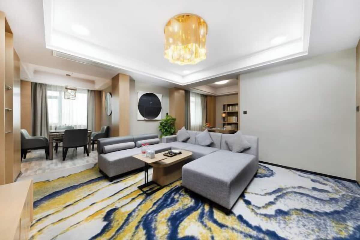Een moderne hotelkamer met een bank, een salontafel, een eethoek en een groot raam.