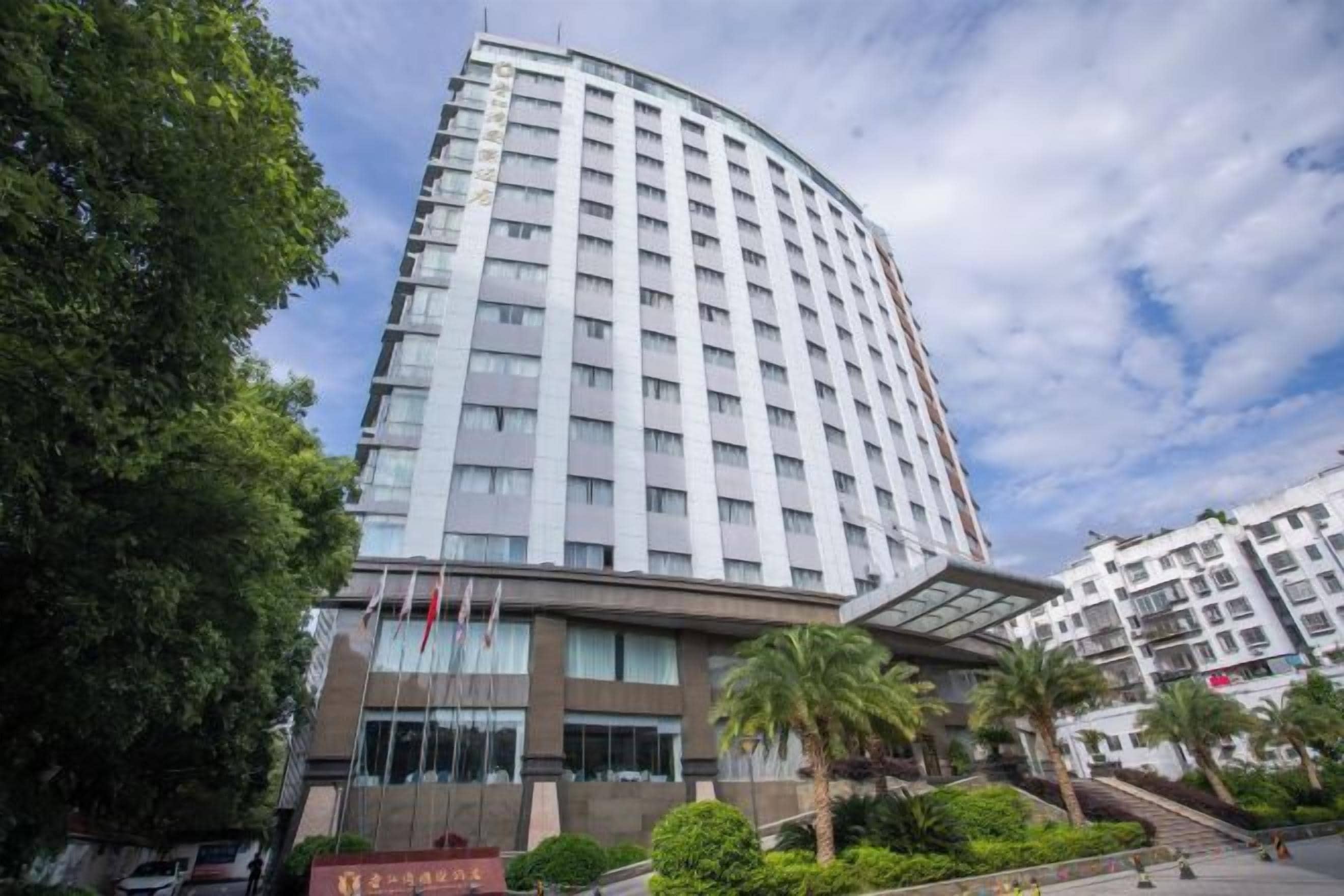 A multi-story hotel with a curved facade, large windows, and a covered entrance area.