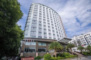 Un hotel de varios pisos con fachada curva, amplias ventanas y un área de entrada cubierta.