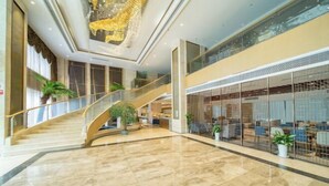 Un hall d’entrée spacieux avec un sol en marbre, un escalier en colimaçon et une rampe en verre.
